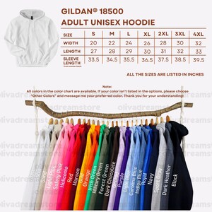 May include: A Gildan 18500 adult unisex hoodie size chart with width, length, and sleeve length measurements in inches. Below, a wooden branch displays a row of hoodies in various colors including white, pink, red, orange, green, blue, and black.