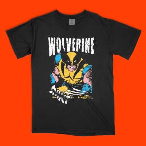 Peut inclure: Un t-shirt noir à manches courtes avec une impression graphique du personnage de bande dessinée Wolverine. Le motif comprend le mot WOLVERINE en lettres blanches usées au-dessus du personnage, représenté avec une armure jaune et bleue.