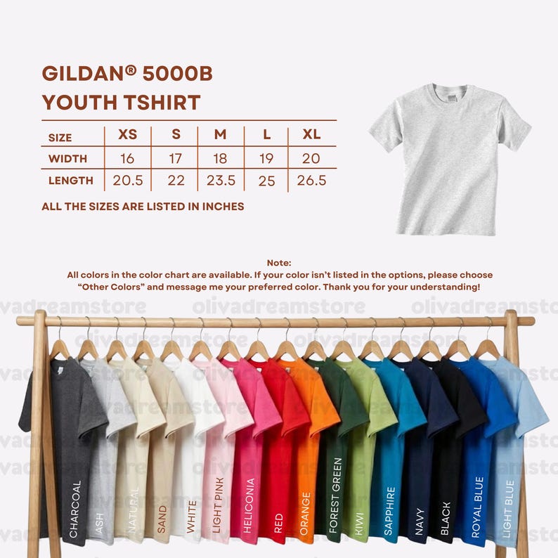 Puede incluir: Exhibici&oacute;n de camisetas Gildan 5000B para j&oacute;venes en varios colores, colgadas en un perchero de madera. La tabla de tallas muestra anchos de 40.6 cm a 50.8 cm y largos de 52.1 cm a 67.3 cm. Colores: carb&oacute;n, ceniza, natural, blanco, etc.