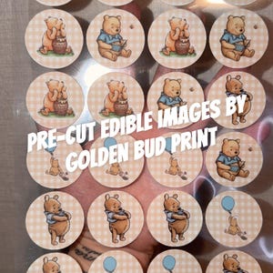 May include: A sheet of circular pre-cut edible images featuring Winnie the Pooh illustrations on a light beige gingham background. The text PRE-CUT EDIBLE IMAGES BY GOLDEN BUD PRINT is printed across the centre of the sheet over the circular designs.