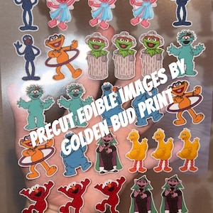 Puede incluir: Una hoja transparente de imágenes comestibles precortadas con varios personajes de dibujos animados, incluyendo un monstruo azul, un hada rosa, un monstruo verde en un cubo de basura, un pájaro amarillo y un vampiro. El texto PRECUT EDIBLE IMAGES BY GOLDEN BUD PRINT es visible.