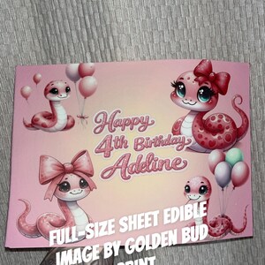 Op de afbeelding: Een roze eetbaar vel met een cartoon slangenontwerp. Op het vel staat "Happy 4th Birthday Adeline" en "Full-Size Sheet Edible Image by Golden Bud Print". De slangen hebben strikken en houden ballonnen vast.
