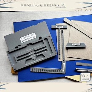 Könnte beinhalten: Ein graues Case Making Multi-Tool-Set mit Linealen und Kartonteilen. Das Set enthält einen Koffer mit der Aufschrift "CASE MAKING MULTI-TOOL SET", ein Lineal mit 20 mm und ein weiteres mit 8 mm. Das Bild zeigt auch ein Lineal mit 3,0 mm.