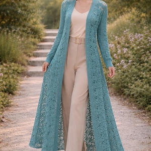 Pode incluir: Cardigã longo de crochê turquesa com frente aberta e delicado padrão floral. O cardigã é usado sobre um top creme e calças bege. O conjunto é completado com um cinto e sandálias a condizer. O cardigã estende-se até aos tornozelos.