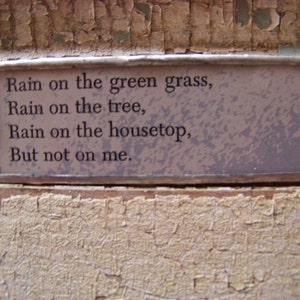 Puede incluir: Un poema enmarcado con el texto "Rain on the green grass, Rain on the tree, Rain on the housetop, But not on me."