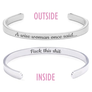 May include: A silver-colored cuff bracelet with the text "A wise woman once said..." on the outside and "Fuck this shit" on the inside. The word "OUTSIDE" is above the bracelet, and "INSIDE" is below it.