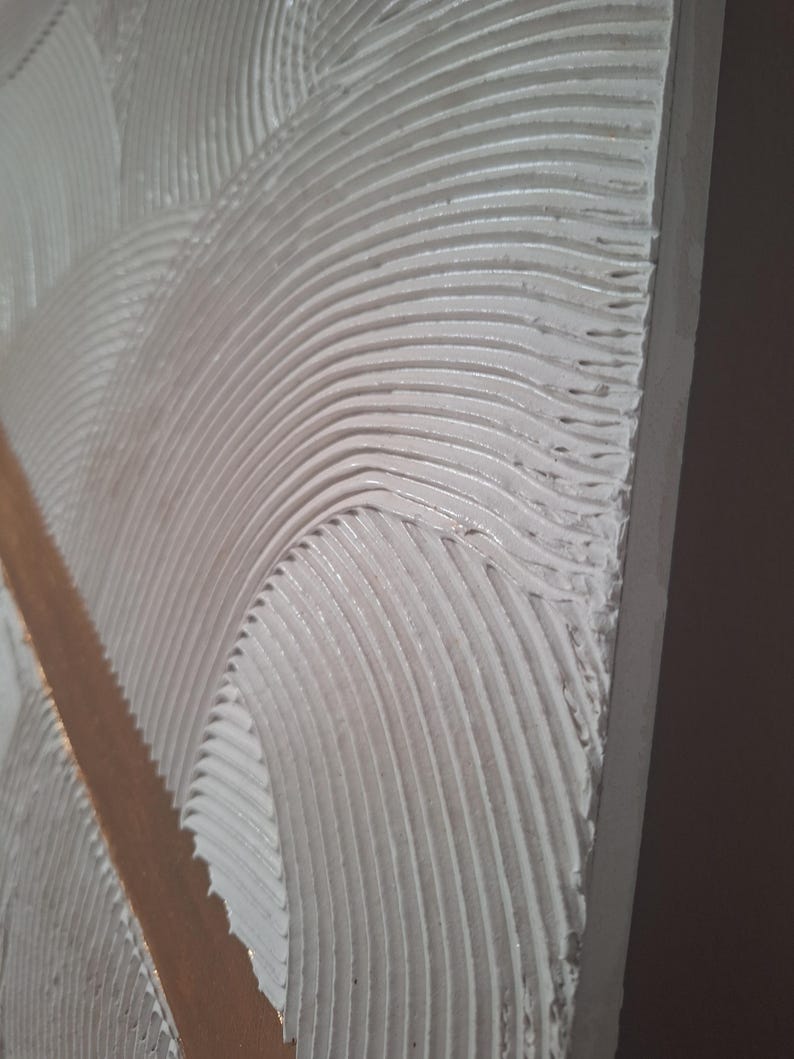 May include: Close-up of a textured, white surface with curved, parallel lines. A vertical, light brown strip bisects the design. The texture appears to be applied with a trowel, creating a wave-like pattern.