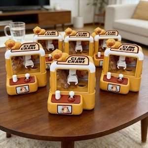 May include: A collection of yellow and white claw crane arcade game toys. Each toy has a bear figure on top and the words "CLAW CRANE" printed on the top. The control panel has two white knobs and a small picture of a bear.