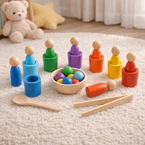 Könnte beinhalten: Ein farbenfrohes Holzspielzeug-Set mit Figuren in verschiedenen Farben, einer Holzschale mit farbigen Kugeln, einem Holzlöffel und einer Holzpinzette. Das Set enthält blaue, grüne, violette, orange, gelbe und rote Elemente.