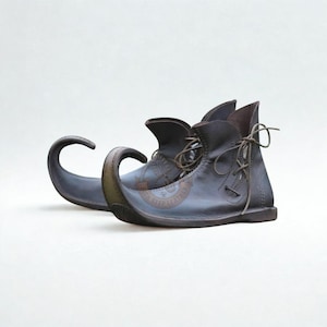 Puede incluir: Un par de botas de cuero marrón oscuro con una punta alargada curvada hacia arriba y cierre de cordones en el tobillo. El lateral de la bota muestra un logotipo circular con el texto IRON STEP LEATHER. El diseño incluye costuras visibles.