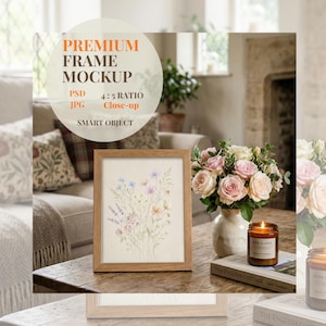 May include: A framed watercolor print of wildflowers in a light brown wooden frame. The image is on a wooden table with a vase of roses, a candle, and a book. The text "PREMIUM FRAME MOCKUP" is at the top.