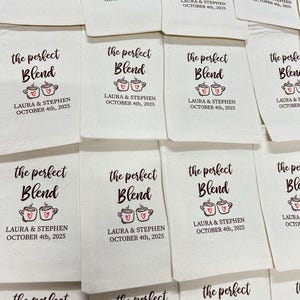 May include: Off-white fabric favor bags with the text "the perfect Blend" in a script font, along with two coffee cup illustrations with hearts. The text "LAURA & STEPHEN OCTOBER 4th, 2025" is also printed on the bags.