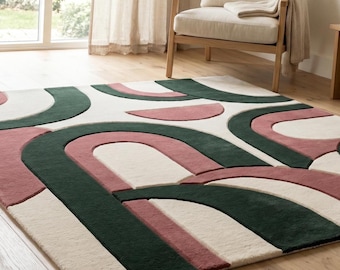 Puede incluir: Una alfombra rectangular con un patrón geométrico de arcos y semicírculos entrelazados. El diseño consiste en un fondo de color crema con formas texturizadas en relieve en tonos verde bosque profundo y rosa palo apagado.