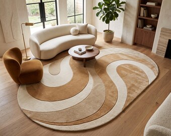 Puede incluir: Una alfombra ovalada con un patrón abstracto a gran escala de líneas curvas y fluidas en tonos alternos de crema, beige y bronceado cálido. La alfombra tiene una textura suave y afelpada sobre el suelo de madera.