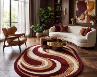 Puede incluir: Una alfombra ovalada con un patrón de remolinos en capas en tonos burdeos intenso, bronceado cálido y crema. La alfombra está colocada sobre un suelo de madera oscura en una habitación con un sofá blanco curvo y una mesa de centro.