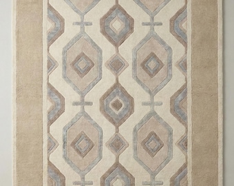 Puede incluir: Alfombra rectangular con un patrón geométrico en beige, gris y marrón. La alfombra presenta un diseño central de diamantes y hexágonos entrelazados, enmarcado por un borde beige liso. Adecuada para salones y dormitorios.