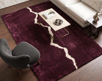 Peut inclure: Un tapis rectangulaire à poils longs et denses, d'une couleur bordeaux profond, traversé par une bande diagonale irrégulière de couleur crème qui crée un contraste visuel marqué avec le fond rouge foncé de la surface du tapis.
