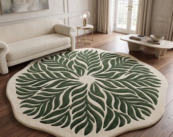 Peut inclure: Un tapis rond de couleur crème orné d'un motif symétrique en forme de feuilles vert foncé rayonnant depuis le centre. Le tapis présente un bord organique ondulé et un aspect touffeté texturé, contrastant avec le parquet en bois foncé.