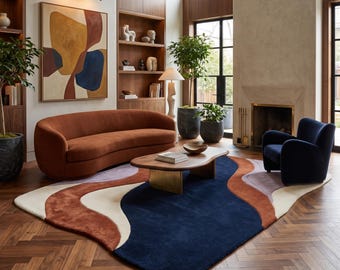 Puede incluir: Una alfombra grande con un patrón orgánico ondulado en azul marino profundo, naranja quemado, crema y lavanda suave. La alfombra tiene una forma curva no rectangular y está colocada sobre un suelo de madera en espiga marrón oscuro.
