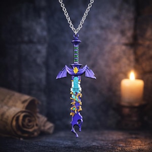 Può includere: Un ciondolo a forma di spada viola e blu con una catena d'argento. La spada presenta un design dettagliato con una gemma gialla e dettagli verdi. Il ciondolo è lungo circa 7.6 cm.