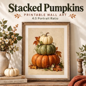 Könnte beinhalten: Ein gerahmtes, druckbares Wandbild mit dem Titel Stacked Pumpkins im 4:5-Hochformat. Das Kunstwerk zeigt einen Stapel aus drei Kürbissen in Weiß, Salbeigrün und Orange, verziert mit Herbstblättern und kleinen weißen Blüten auf beigem Hintergrund.