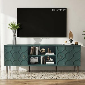 May include: A dark teal media console with two side cabinets featuring a geometric hexagonal pattern, two central open shelves containing books and decorative objects, and four tapered brown legs, positioned below a flat screen TV.