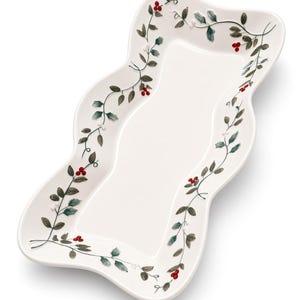 May include: A white ceramic serving tray with a wavy, scalloped edge. The border is decorated with a painted pattern of green holly leaves, thin brown vines, and clusters of small red berries, leaving the center of the tray plain white.