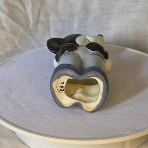 May include: A vintage Mickey Mouse figurine, featuring a black head and ears, white face, and blue overalls. The figurine is ceramic and has a glossy finish. The base is marked with "D12".