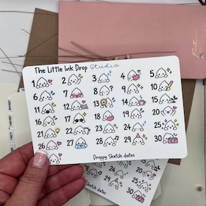 Può includere: Un foglio di adesivi rettangolare bianco intitolato The Little Ink Drop Studio con trenta illustrazioni numerate di un piccolo personaggio bianco a forma di goccia, con il testo Droppy Sketch dates stampato nella parte inferiore.