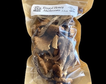 May include: A clear plastic pouch with a brown paper backing containing dried Ringed Honey Mushrooms. The white label at the top displays the text Ringed Honey Mushrooms 1.5 oz along with small black and white illustrations of mushrooms.