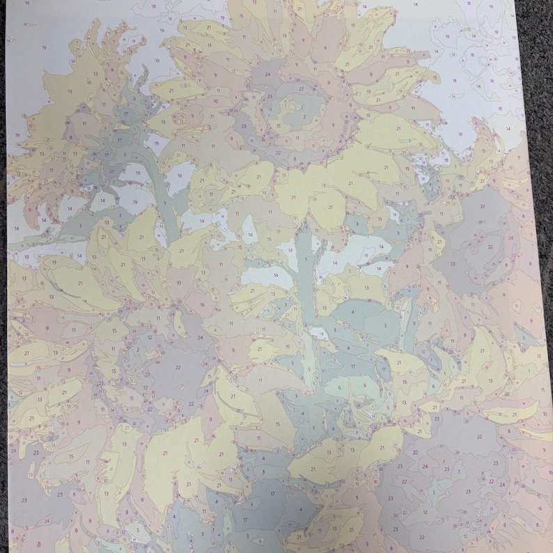 May include: A paint-by-number canvas featuring a floral arrangement of sunflowers. The design is divided into numbered sections with pale yellow, soft green, light blue, and muted beige outlines, providing a guide for applying paint to the surface.