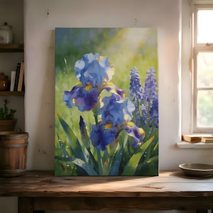 May include: A canvas print depicting a painting of blue iris flowers with yellow centres and purple hues, set against a green backdrop. The artwork shows the flowers in a field with water droplets, lit by sunlight.