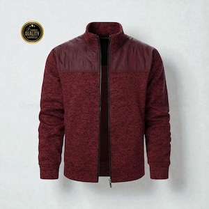 May include: A burgundy zip-up jacket with a high collar. The upper chest area is a solid burgundy color, while the rest of the jacket has a textured knit appearance. A gold-colored emblem with the words "Premium Quality Guaranteed" is in the upper left corner.