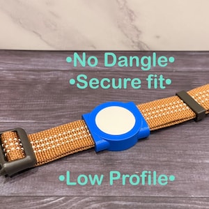 Op de afbeelding: Een bruin en witte dierenhalsband met een blauw-witte cirkelvormige bevestiging. De halsband heeft een zwarte gesp en een veilig ontwerp. De tekst op de afbeelding luidt "No Dangle", "Secure fit" en "Low Profile".