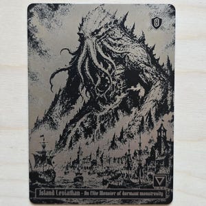 May include: A rectangular metallic trading card featuring a black ink illustration of a massive tentacled creature rising behind a coastal town with ships. The text reads Island Leviathan - An Elite Monster of dormant monstrosity.