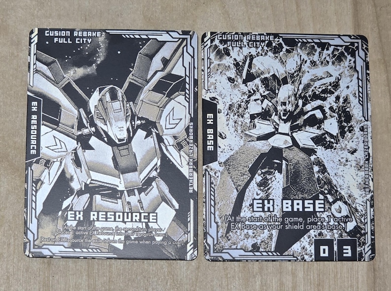 May include: Two trading cards with black and white illustrations of futuristic robots. The card on the left is labeled "EX RESOURCE" and the card on the right is labeled "EX BASE". The cards have text that reads "CUSION REBAKE FULL CITY".