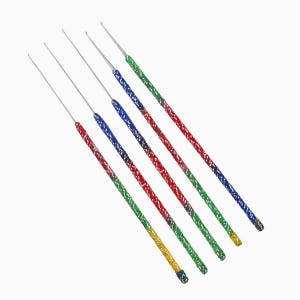 Peut inclure: Un ensemble de cinq crochets avec des pointes métalliques fines et de longs manches texturés. Les manches présentent un motif moucheté multicolore dans des tons de rouge, bleu, vert et jaune, disposés en ligne diagonale sur un fond blanc.
