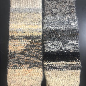 Peut inclure: Deux pièces textiles rectangulaires tricotées à la main. La pièce de gauche présente un dégradé de couleurs du crème au noir, avec des nuances de jaune, de gris et de marron. La pièce de droite a un design similaire, avec des tons noirs, gris et crème. Les deux ont un aspect texturé et flou.