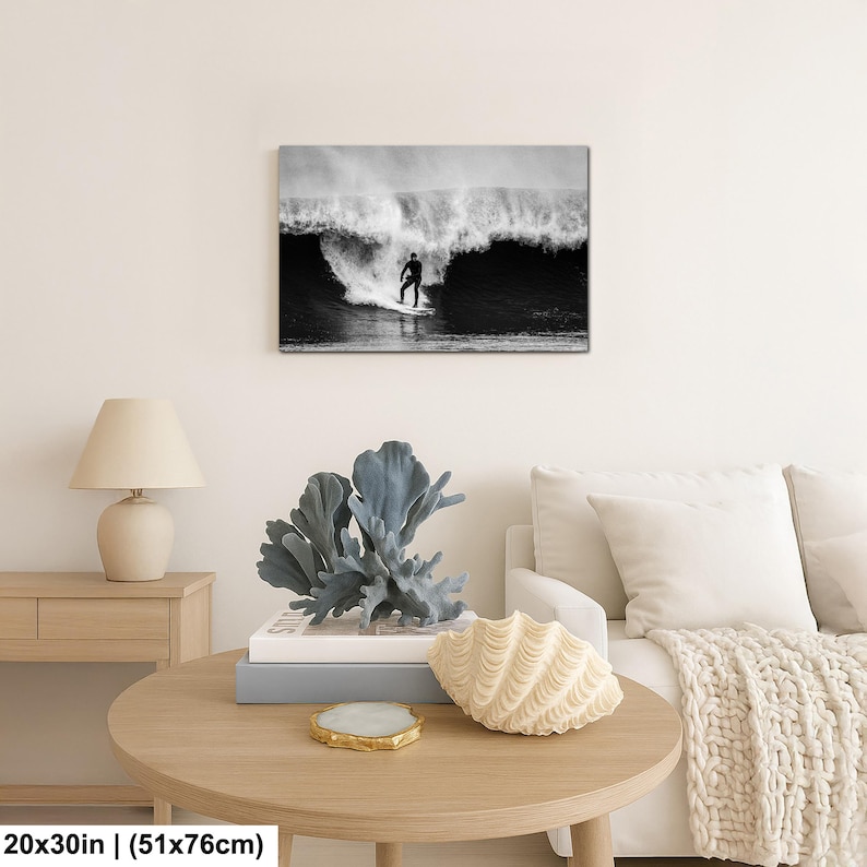 K&ouml;nnte beinhalten: Schwarz-Wei&szlig;-Leinwanddruck eines Surfers, der eine gro&szlig;e Welle reitet. Das Kunstwerk ist 51x76cm gro&szlig;. Der Surfer ist eine Silhouette vor der Welle. Der Druck wird &uuml;ber einem runden Holztisch mit dekorativen Gegenst&auml;nden angezeigt.