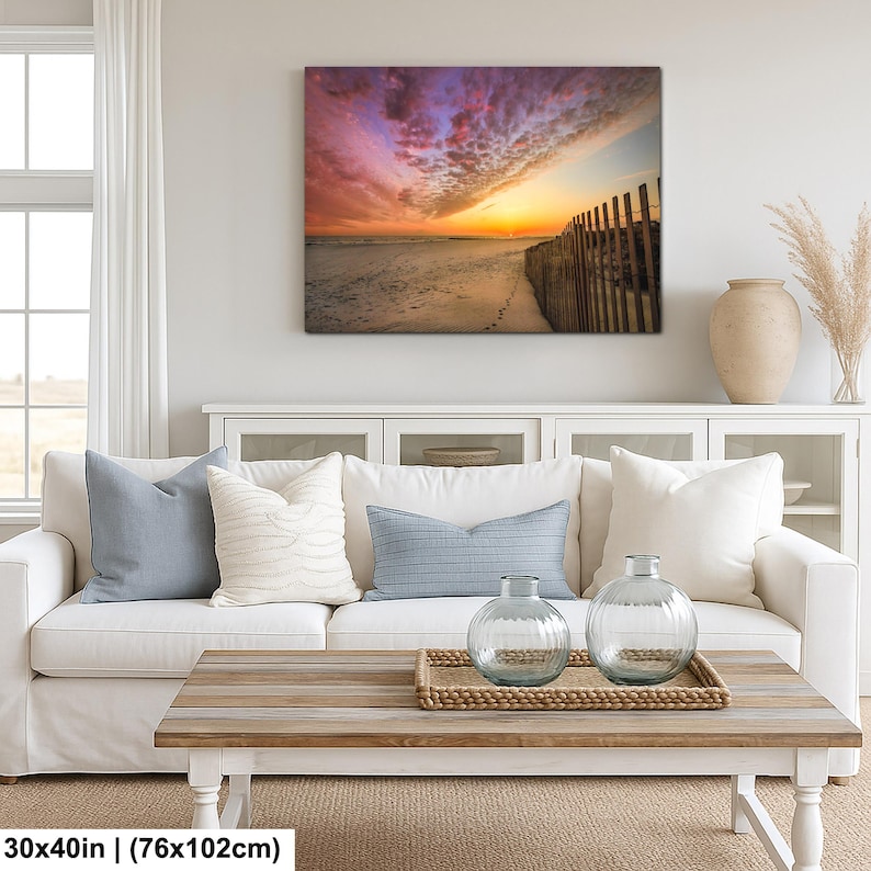 Peut inclure: Impression sur toile d'une sc&egrave;ne de plage au coucher du soleil. Le ciel est un m&eacute;lange de roses, d'oranges et de violets. Une cl&ocirc;ture en bois borde la plage. L'impression mesure 76x102cm.