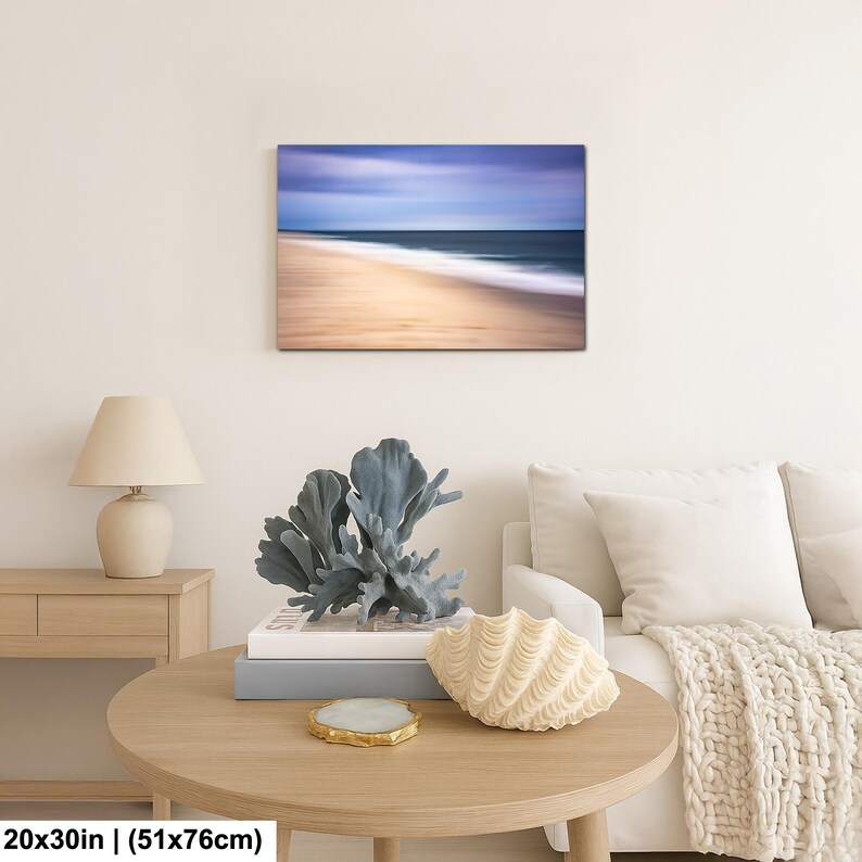 May include: A framed canvas print of a beach scene with a blurred effect. The image features a sandy beach, ocean waves, and a blue sky. The print measures 20x30 inches (51x76cm).