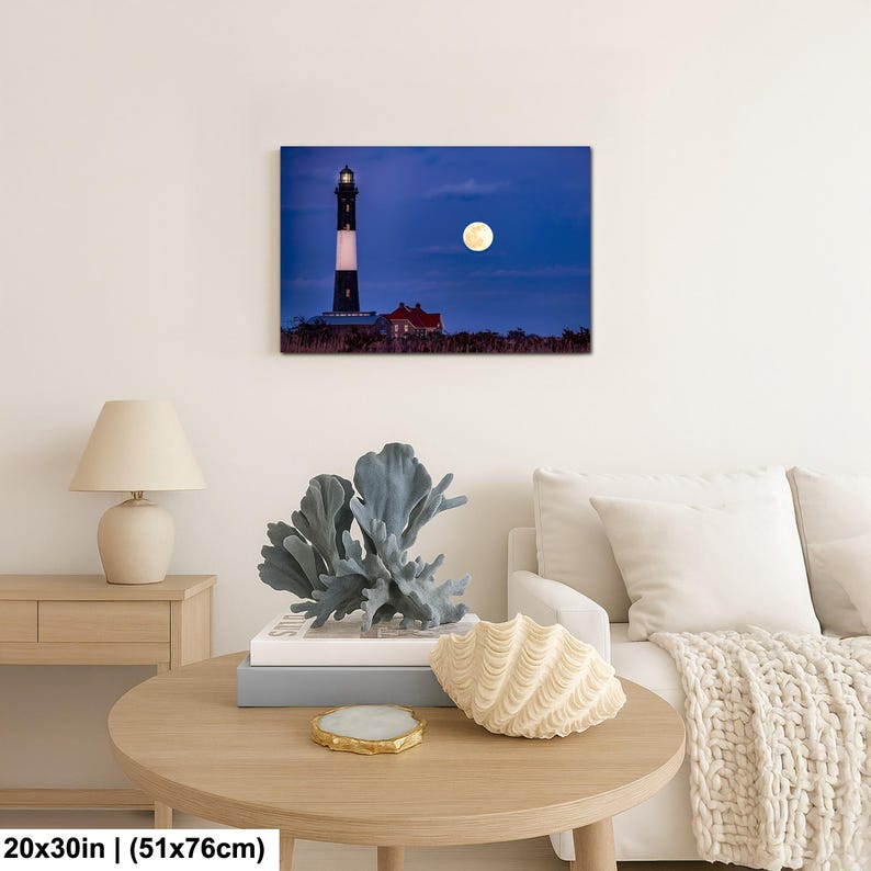 May include: A canvas print of a lighthouse at night, with a full moon in the sky. The lighthouse is black and white, and the moon is a bright yellow. The print measures 20x30 inches.