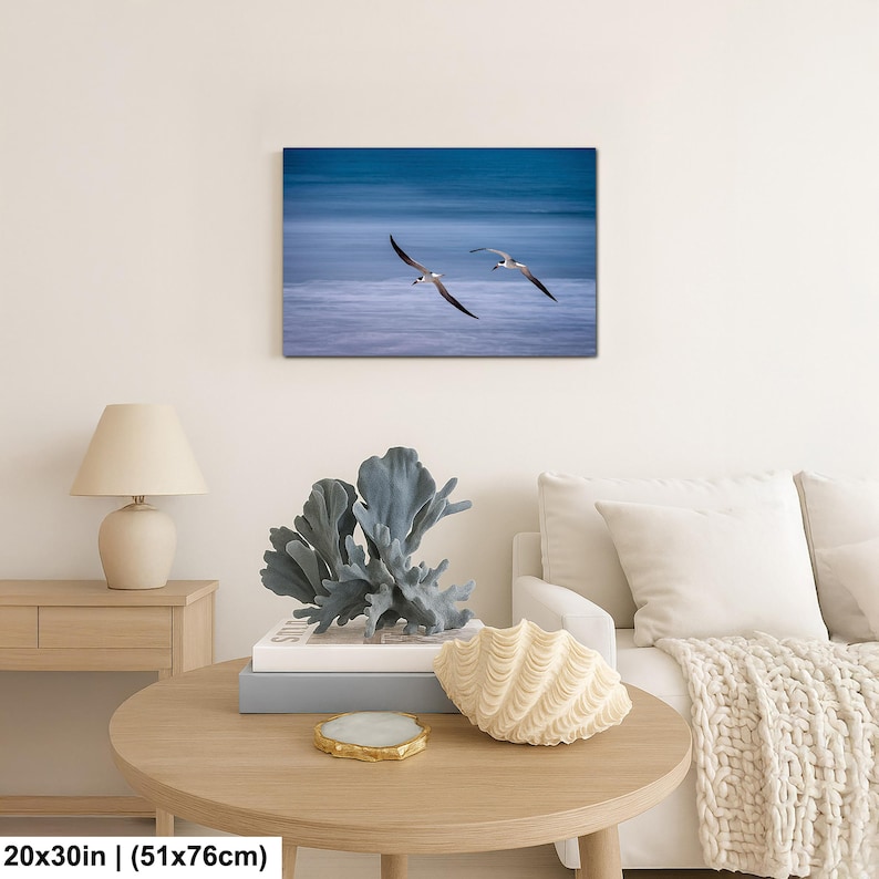 May include: A canvas print featuring two birds in flight over a blue ocean. The birds have black and white markings and are captured mid-flight. The artwork is 20x30 inches.