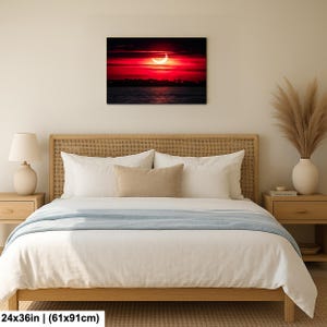 Pode incluir: Impress&atilde;o em tela emoldurada de um p&ocirc;r do sol com uma lua crescente. O c&eacute;u &eacute; vermelho vibrante com nuvens escuras, e a lua &eacute; branca brilhante. A impress&atilde;o mede 61x91cm.