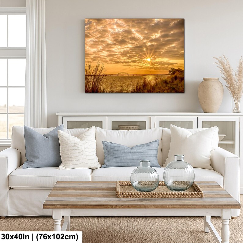 May include: A canvas print depicting a sunset over water, with a bridge in the distance. The sky is filled with golden clouds, and the print measures 30x40 inches.