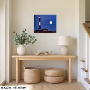 May include: A framed print of a lighthouse under a full moon. The lighthouse is black and white, with a red building at its base. The print is 16x20 inches (41x51cm). The scene is set against a dark blue sky.