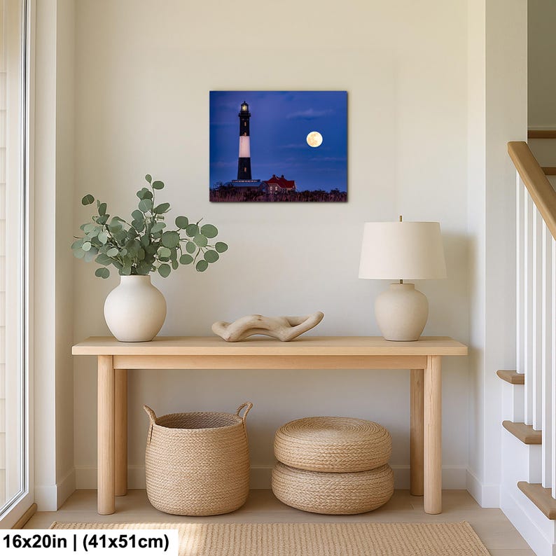 May include: A framed print of a lighthouse under a full moon. The lighthouse is black and white, with a red building at its base. The print is 16x20 inches (41x51cm). The scene is set against a dark blue sky.