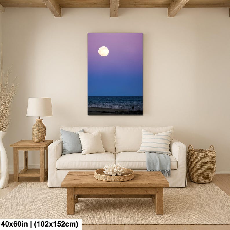 May include: A vertical canvas print depicts a serene beach scene at dusk. The sky transitions from purple to blue, with a full moon. The ocean meets the shore, and a silhouetted figure stands on the beach. The canvas measures 40x60 inches.
