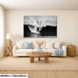 K&ouml;nnte beinhalten: Schwarz-Wei&szlig;-Leinwanddruck eines Surfers auf einer Welle. Das Kunstwerk h&auml;ngt &uuml;ber einem wei&szlig;en Sofa in einem Wohnzimmer. Das Bild misst 102x152cm.