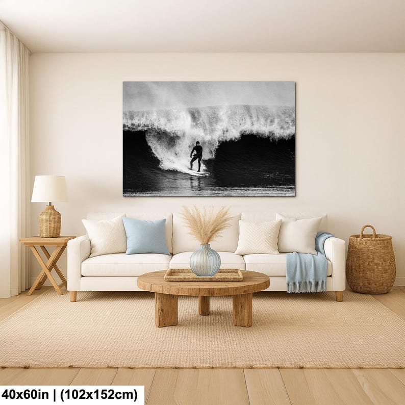 K&ouml;nnte beinhalten: Schwarz-Wei&szlig;-Leinwanddruck eines Surfers auf einer Welle. Das Kunstwerk h&auml;ngt &uuml;ber einem wei&szlig;en Sofa in einem Wohnzimmer. Das Bild misst 102x152cm.
